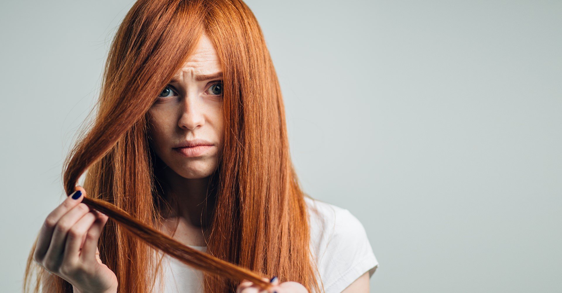 Modelo branca com cabelo ruivo e expressão de tristeza